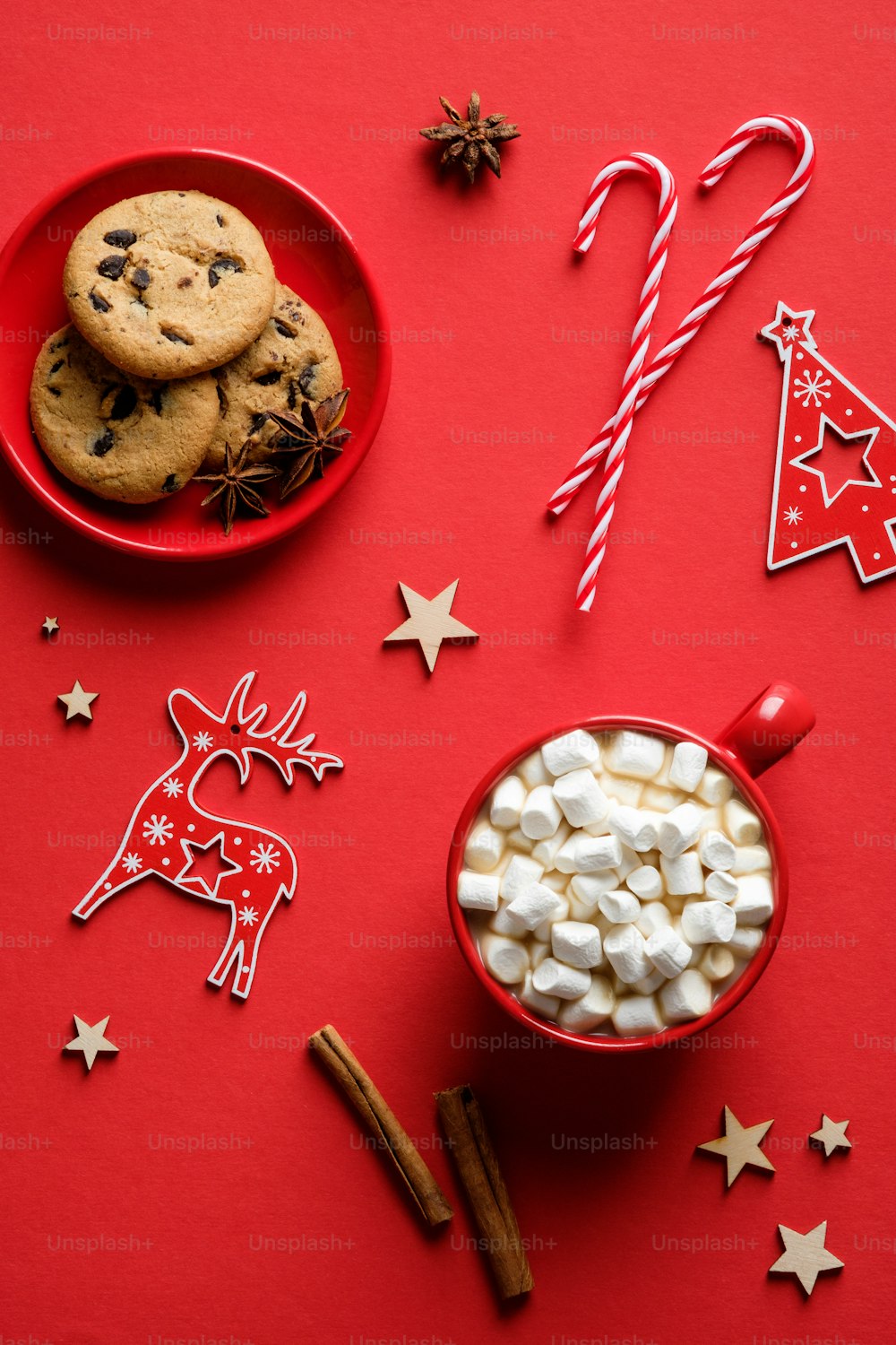 Composizione natalizia con biscotti di farina d'avena, bastoncini di zucchero, bastoncini di cannella, cioccolata calda su sfondo rosso. Posa piatta, vista dall'alto