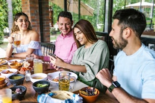 Gruppo di giovani amici latini che si incontrano per birra, bevande michelada e cibo messicano che fa un brindisi nella terrazza del ristorante in Messico America Latina