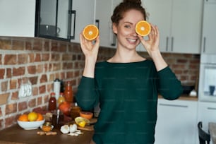Caucasian young woman covering eyes with orange halves