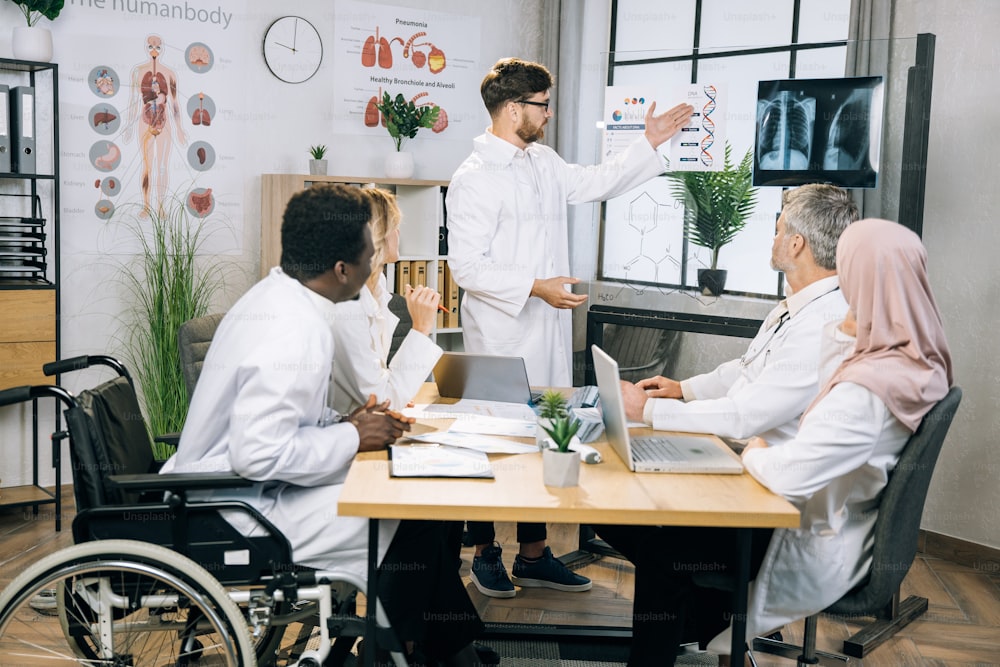 Group of multiracial medical workers discussing gene modification while sitting together at bright office. Qualified doctors researching dna peculiarities during international conference.