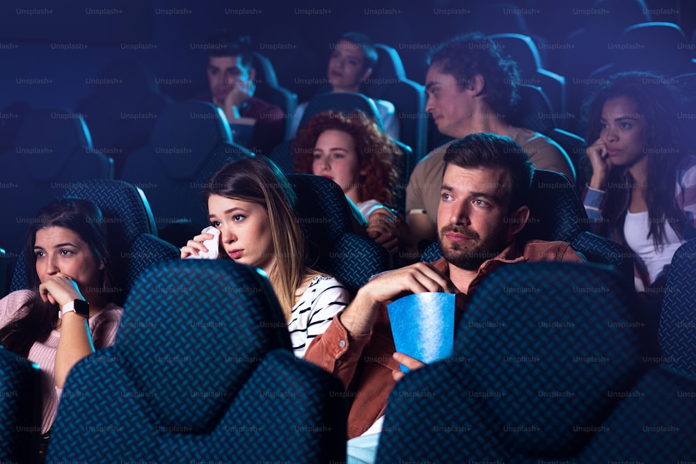 Group of people watching sad movie in cinema.