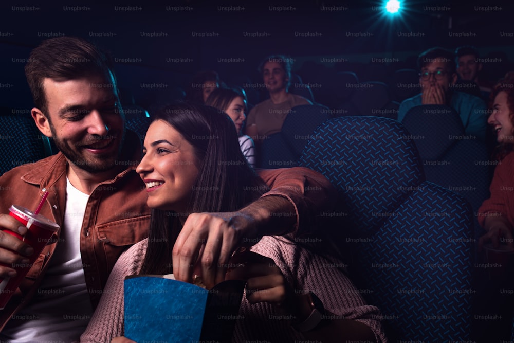 Grupo de pessoas alegres rindo enquanto assiste a filmes no cinema.