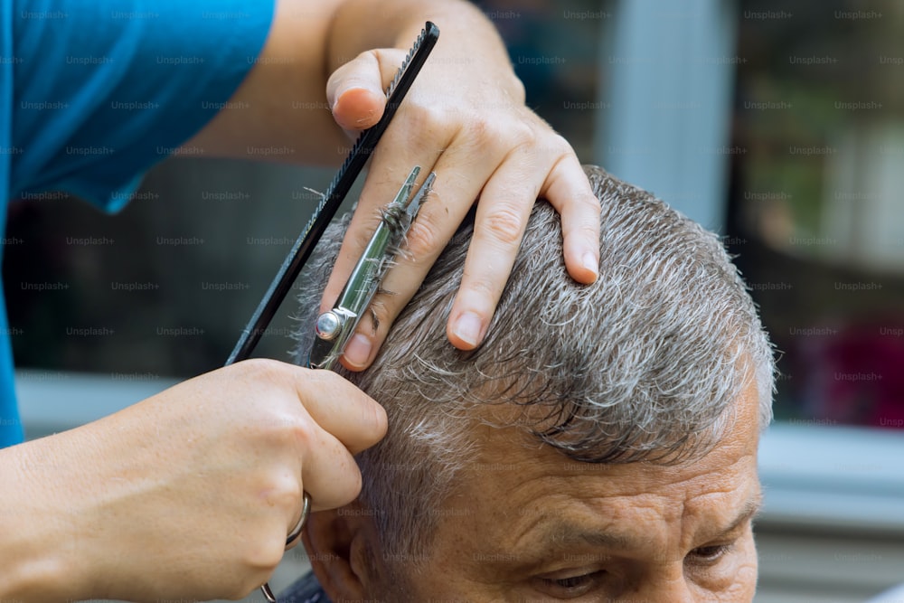 A Barber hairdresser stylish haircut for a man in a home