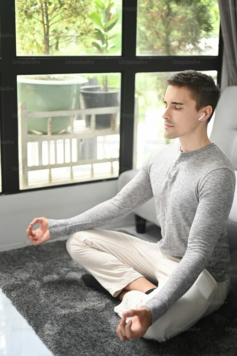 Peaceful young man practicing yoga in living room.