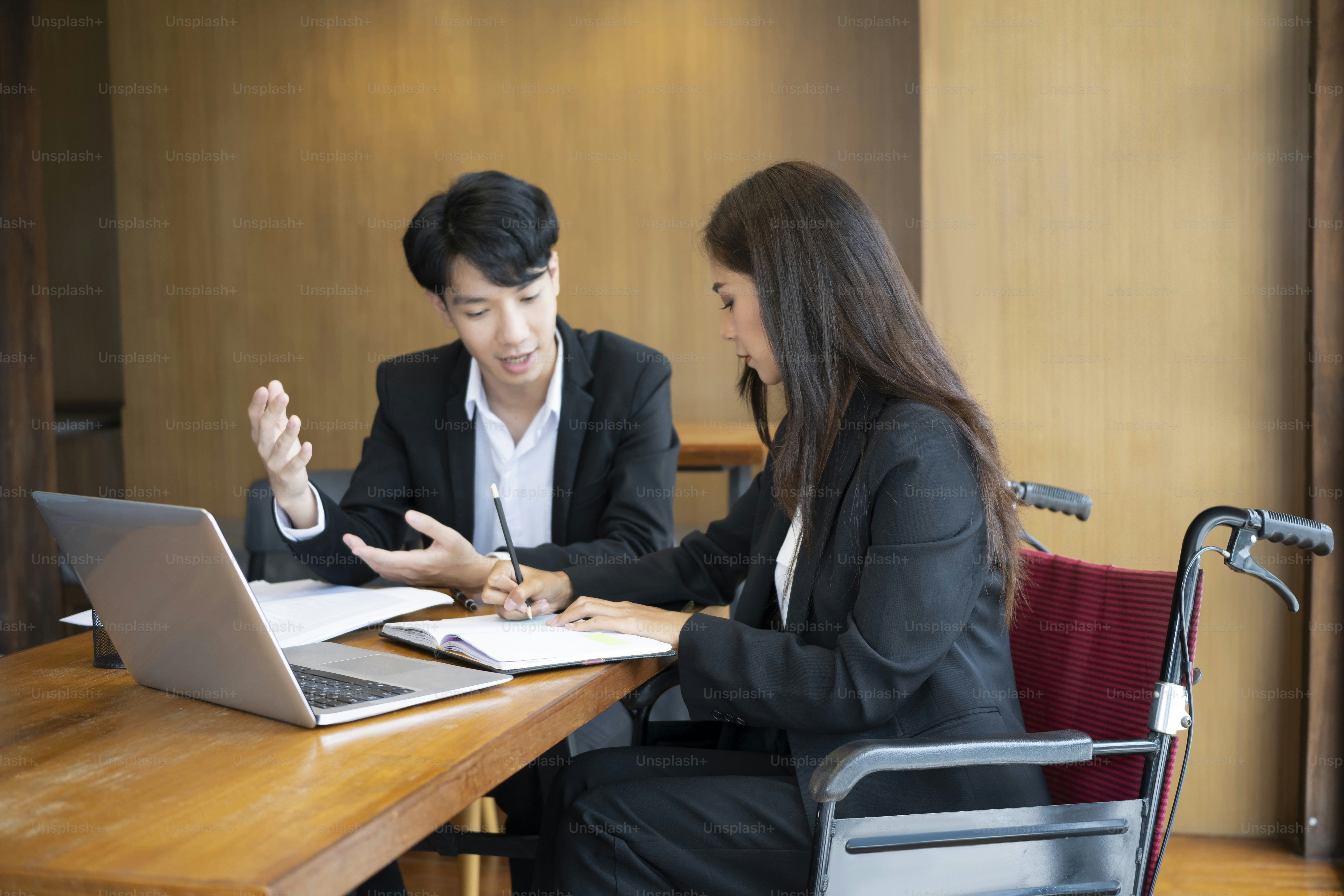 Businesswoman in wheelchair working on new business project with her colleague in office.