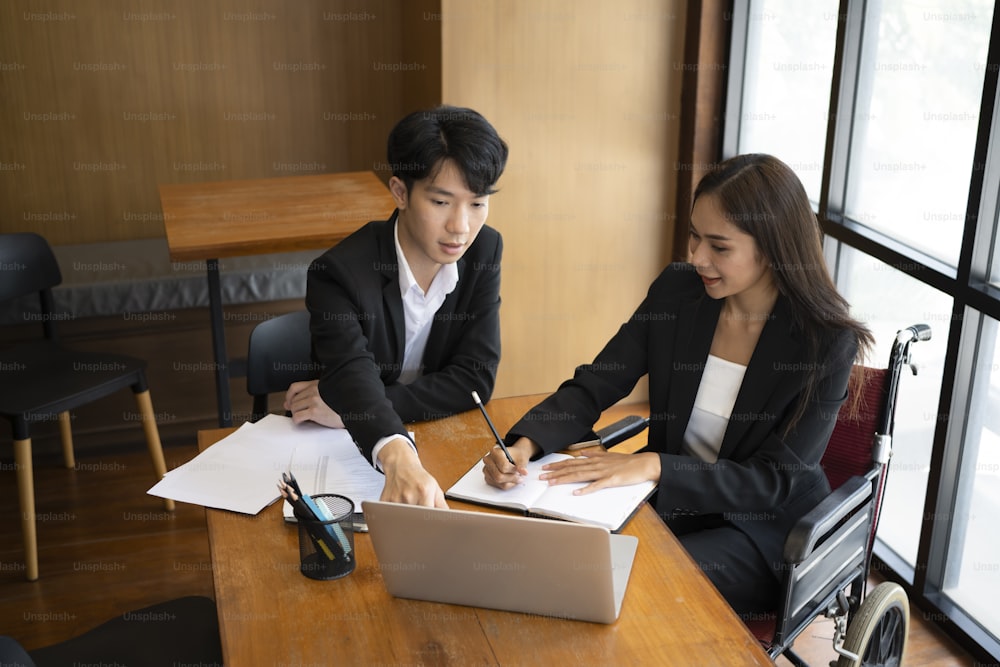 Smiling businessman in wheelchair working with colleagues in office.