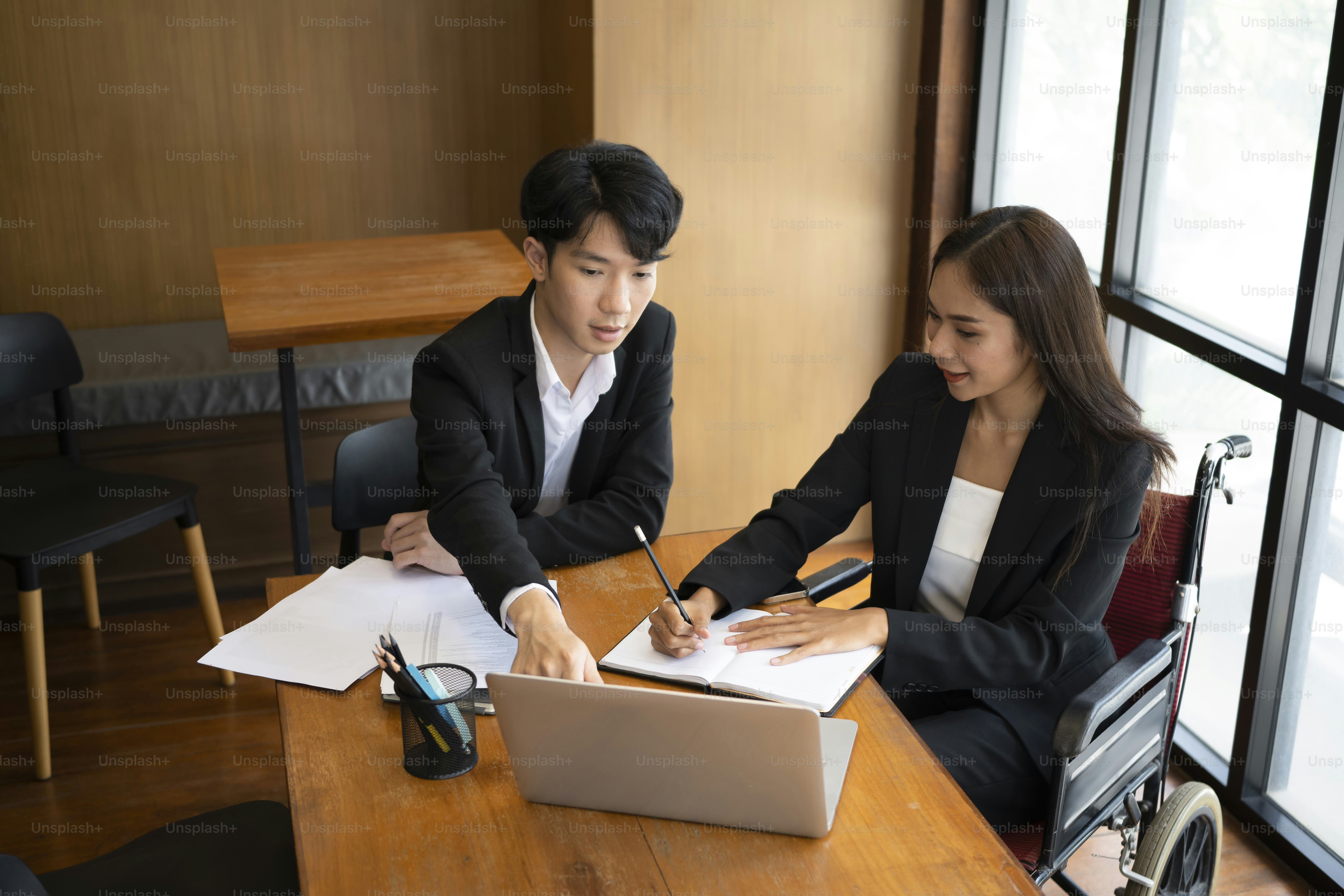 Smiling businessman in wheelchair working with colleagues in office.