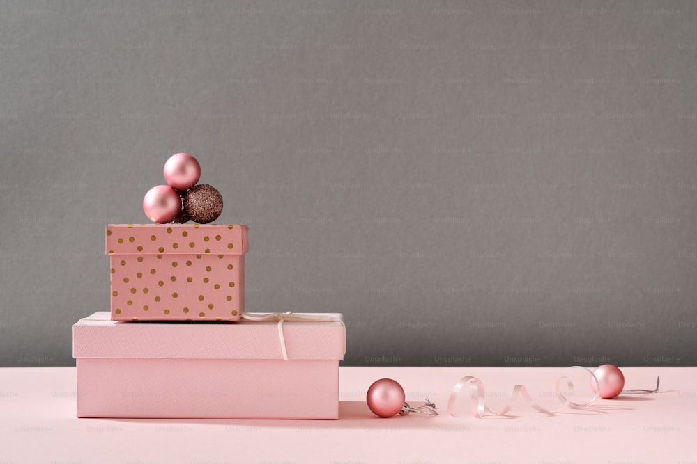 Boxes with Christmas presents and ornaments on pastel pink background with copy space