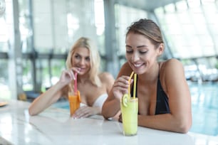 Zwei schöne Frauen entspannen sich im Pool mit Cocktails.Poolbar im tropischen Ferienort Urlaubsziel
