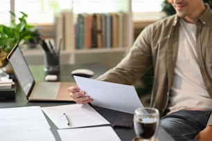 Young man entrepreneur sitting in home office and reading financial documents.