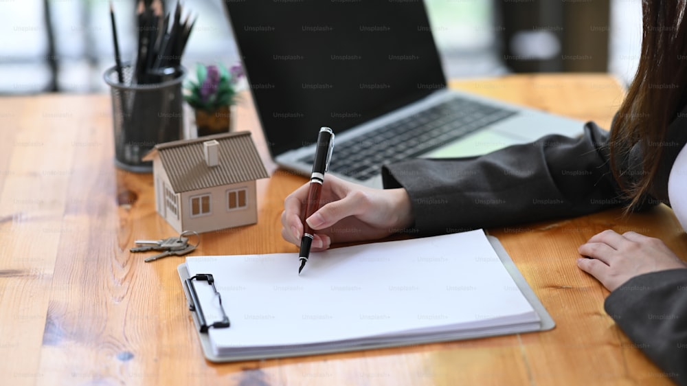 Immobilienmaklerin analysiert Immobilieninvestitionsdaten auf Holztisch.