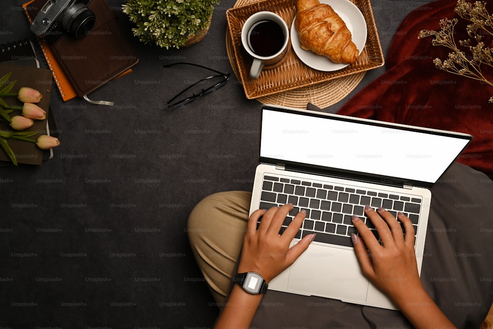 Mujer joven sentada en la alfombra y usando una computadora portátil.
