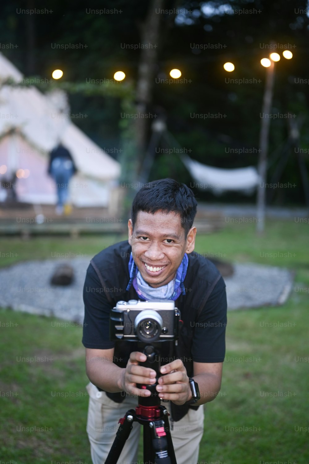 Young man traveler taking photo or video near camping tents.