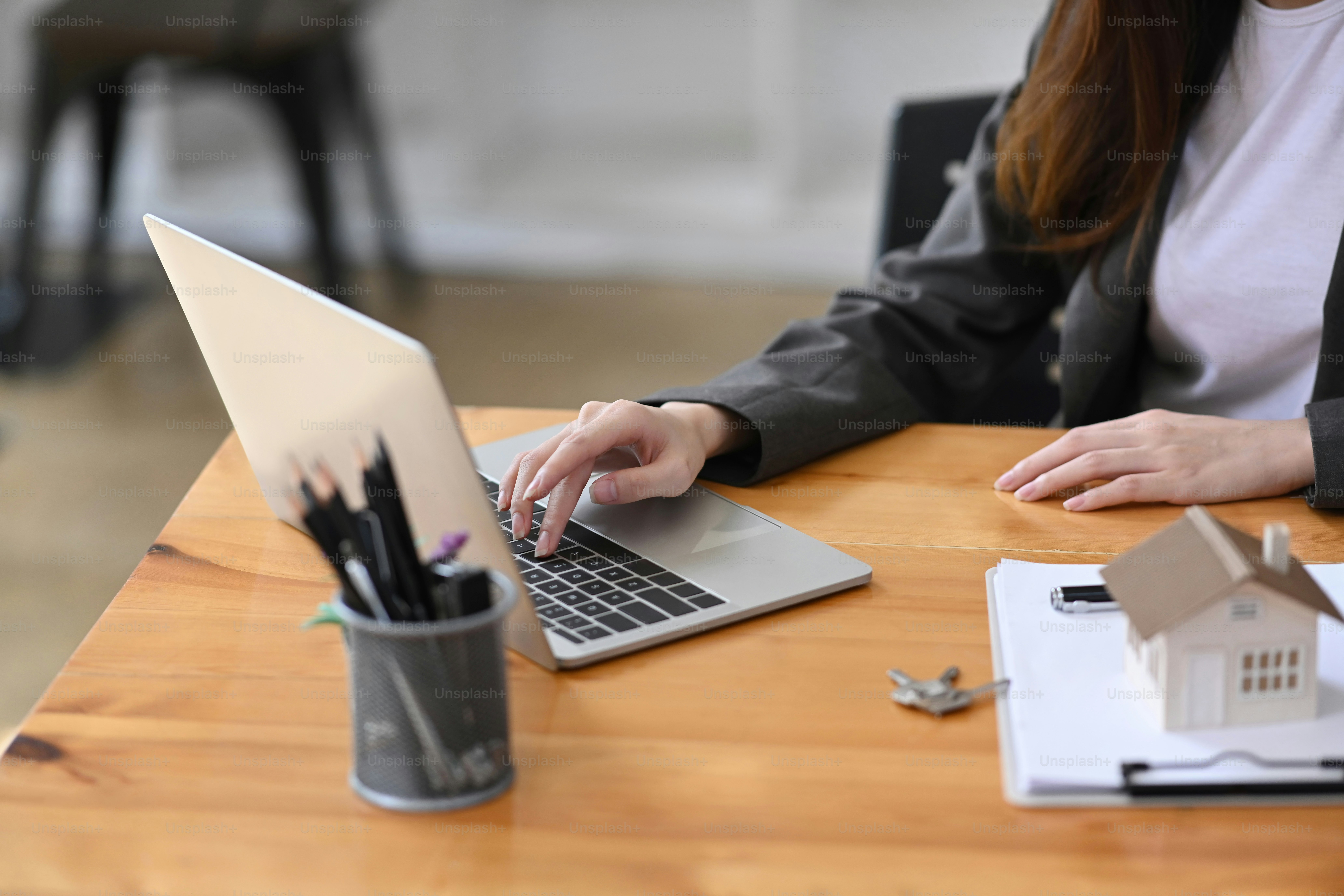 Real estate agent working with laptop computer in her office room. Mortgage and real estate investment.