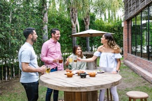 Group of Young latin Friends Meeting For beer, michelada Drinks And mexican Food Making A Toast In Restaurant terrace in Mexico Latin America