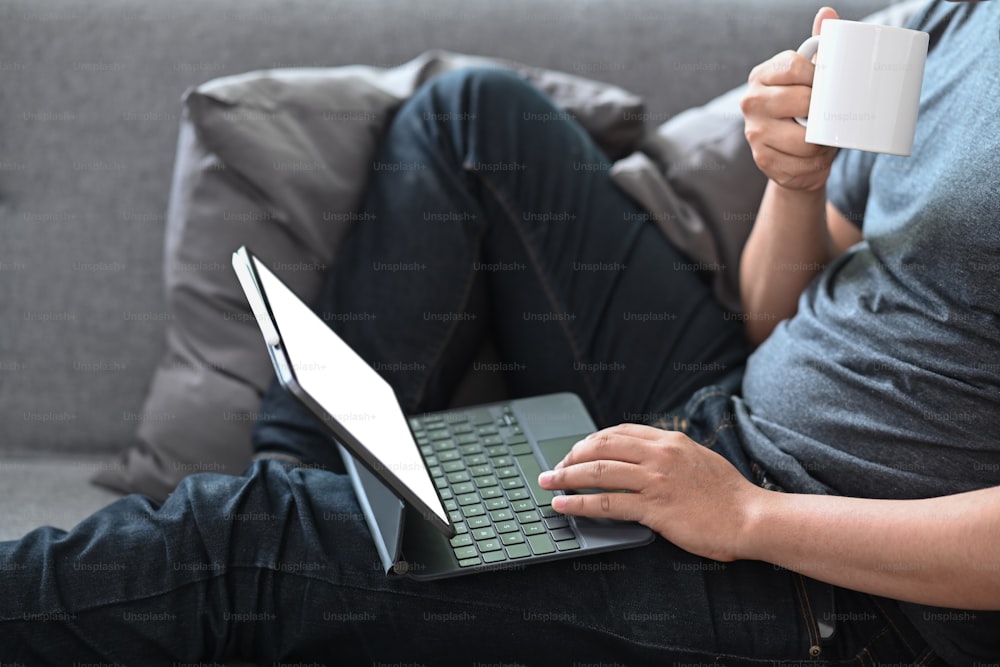 Young man sitting on couch and using computer tablet.