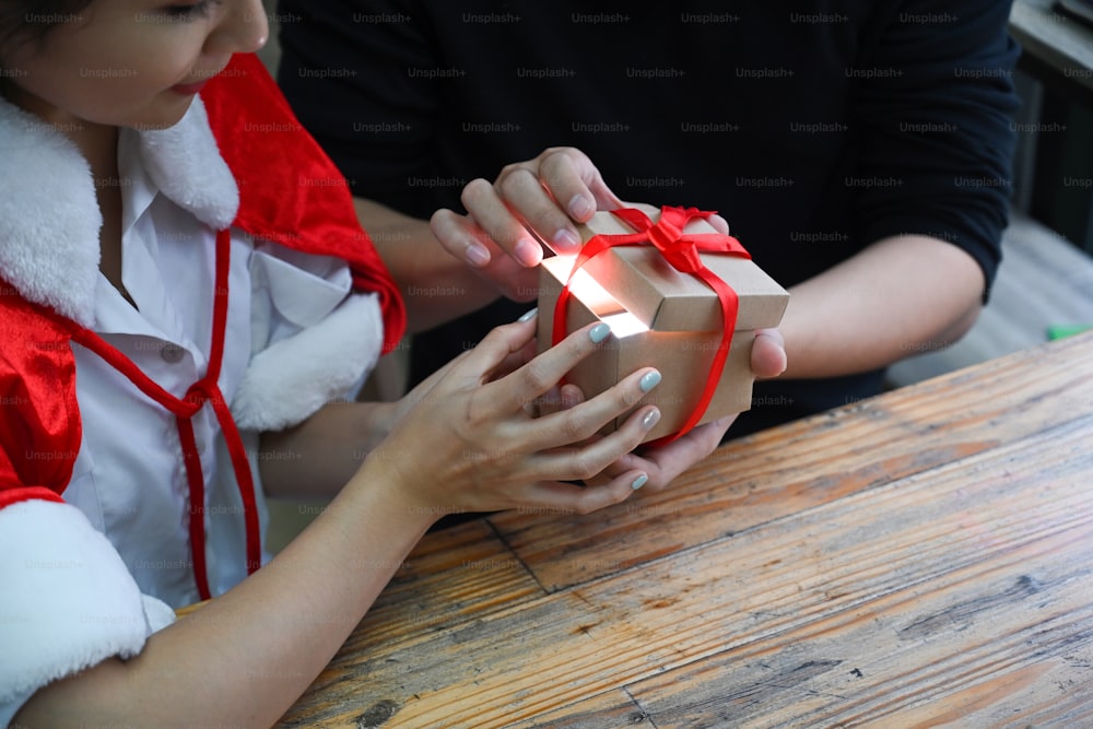 Cropped shot young couple opening Christmas gift box together.