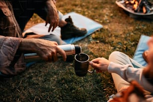 魔法瓶を使い、一緒にキャンプをしながら飲み物を飲む男と成熟した父親の接写。