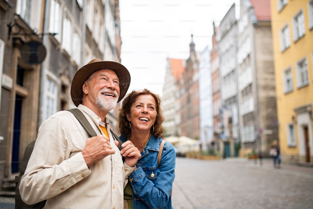 Um retrato de turistas felizes do casal sênior ao ar livre na cidade histórica