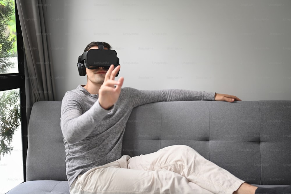 Jeune portant un casque de réalité virtuelle et jouant à un jeu vidéo ou regardant un film à la maison.