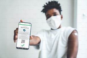 African American teenager shows vaccine passport on mobile phone to validate travel permission by the digital document