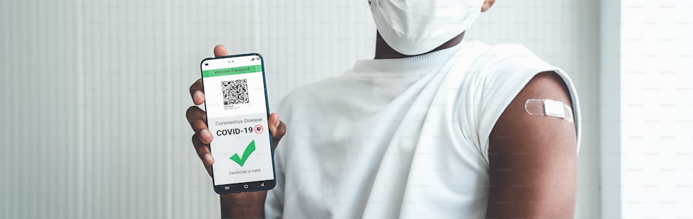 아프리카 계 미국인 십대는 디지털 문서로 여행 허가를 확인하기 위해 휴대 전화에 백신 여권을 보여줍니다.