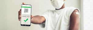 African American teenager shows vaccine passport on mobile phone to validate travel permission by the digital document