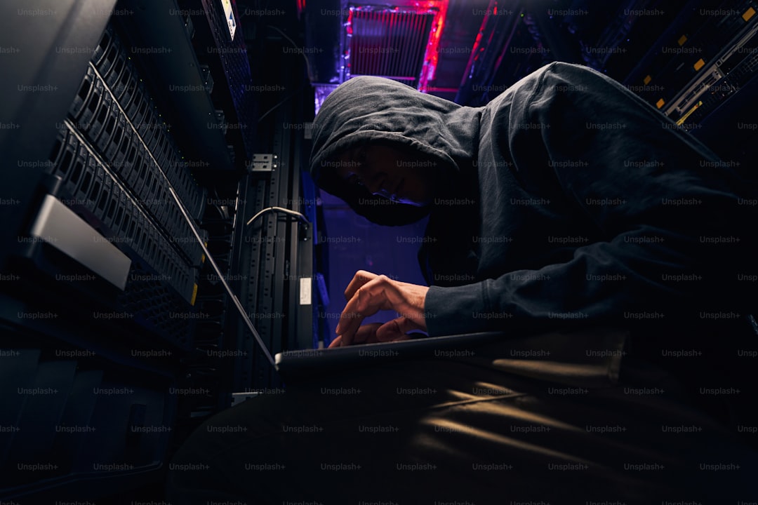 Low angle of hacker installing malicious software on data center servers using laptop