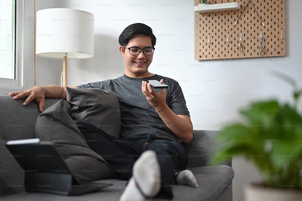 Smiling man talking on mobile phone while sitting in living room.