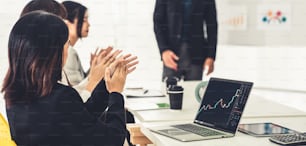 Businesswoman in analyze stock market data using laptop computer proficiently at the office while attending a group meeting with business team .