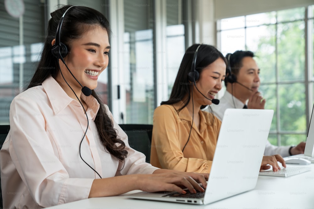 Gente de negocios que usa auriculares que trabajan activamente en la oficina. El centro de llamadas, el telemarketing y el agente de atención al cliente brindan servicio en llamadas telefónicas de videoconferencia.