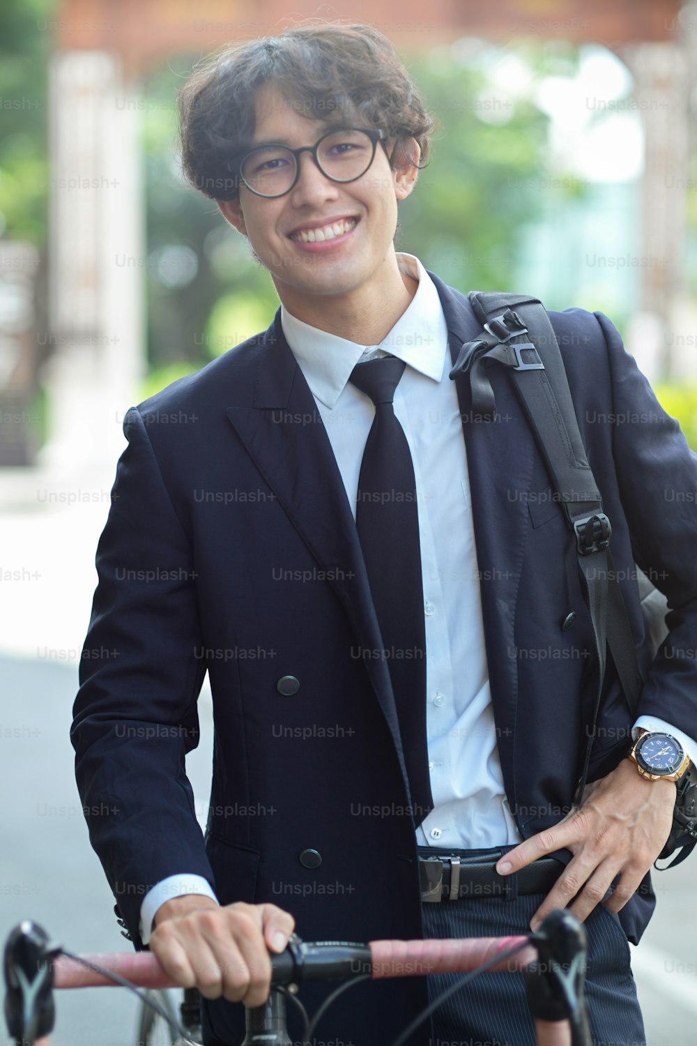 Portrait of successful millennial businessman in formal suit with backpack and bicycle on the street