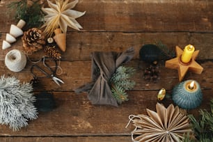 Elegante regalo di Natale avvolto in tessuto con ramo di abete su tavolo in legno rustico con decorazioni natalizie. Vacanze invernali a rifiuti zero e regalo flat lay. Furoshiki regalo ecologico