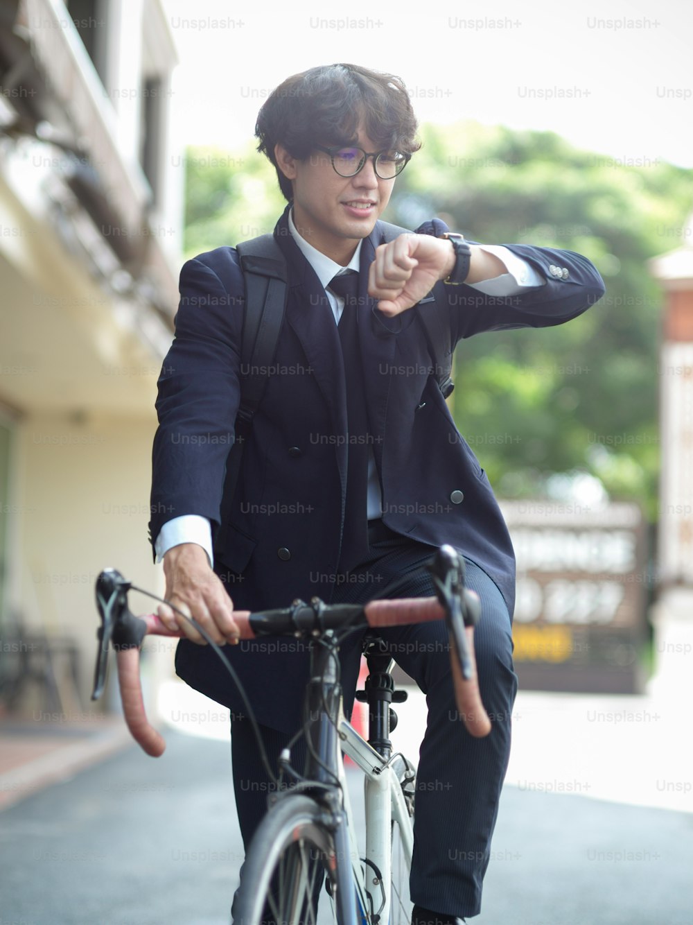 Young urban businessman riding on bicycle to commute to work in a rush hour in the morning. Successful businessman go to work by bicycle.