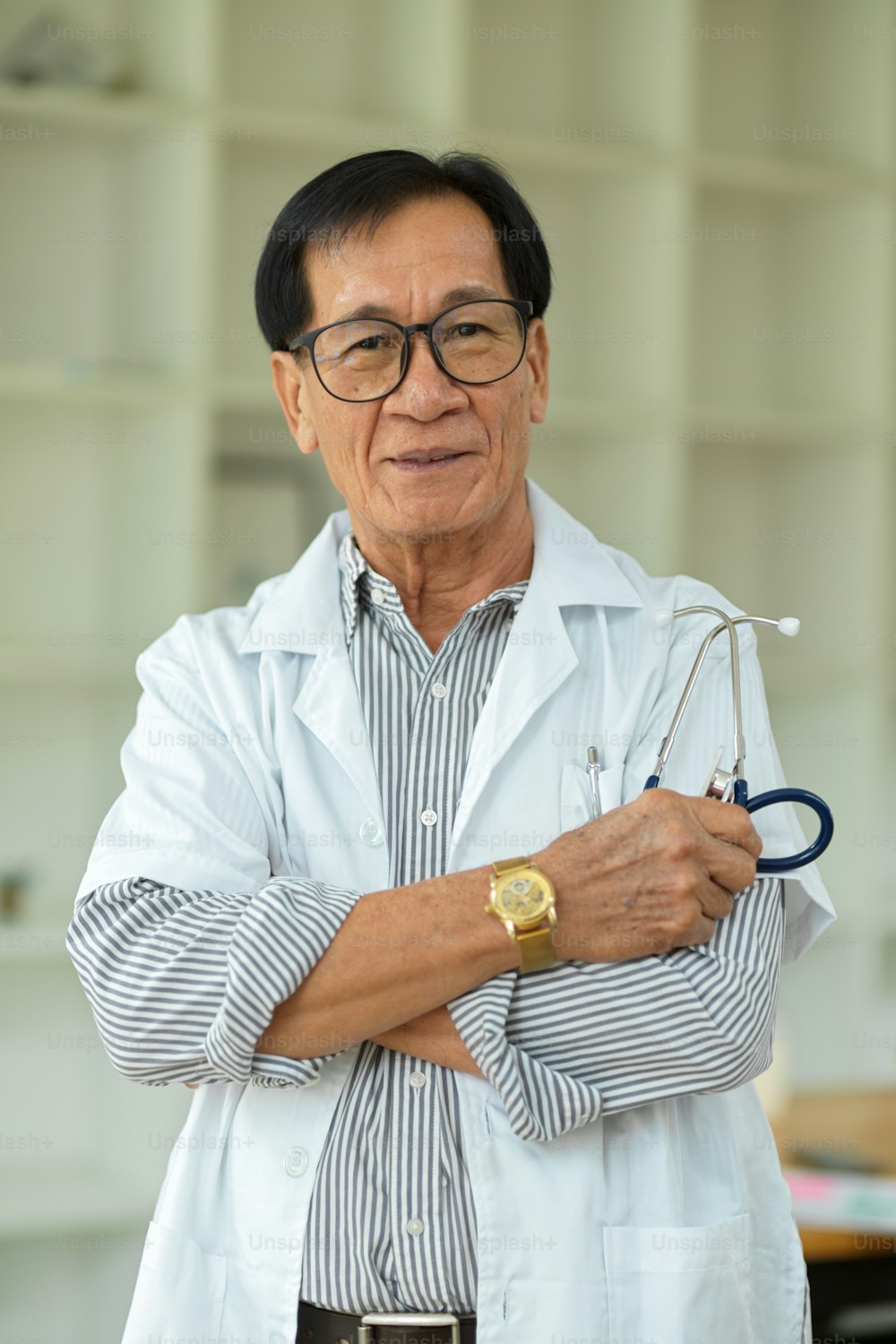 Retrato de un médico especialista de mediana edad exitoso y seguro de sí mismo cruzado de brazos en bata médica blanca.