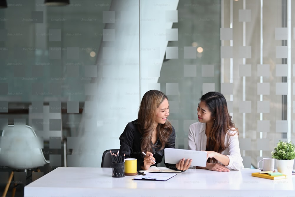 Two young business women discussing business plan together.