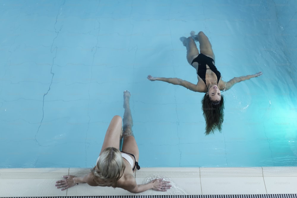 Toma de retrovisor de dos mujeres jóvenes relajándose en la piscina de un spa