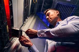 Niedriger Winkel des fokussierten qualifizierten IT-Technikers, der das Festplattenlaufwerk in den Netzwerkcomputer einführt
