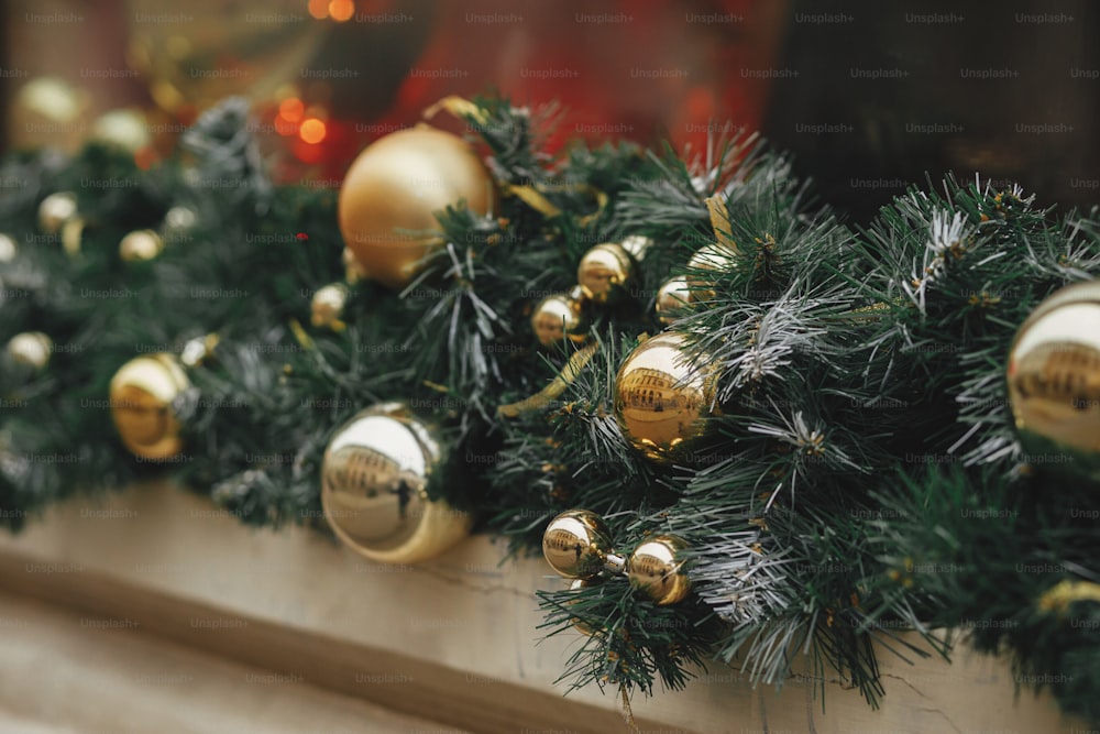 Stylish christmas spruce branches and gold baubles decoration on window of buildings or shop. Christmas festive street decor for winter holidays in european city street. Merry Christmas!