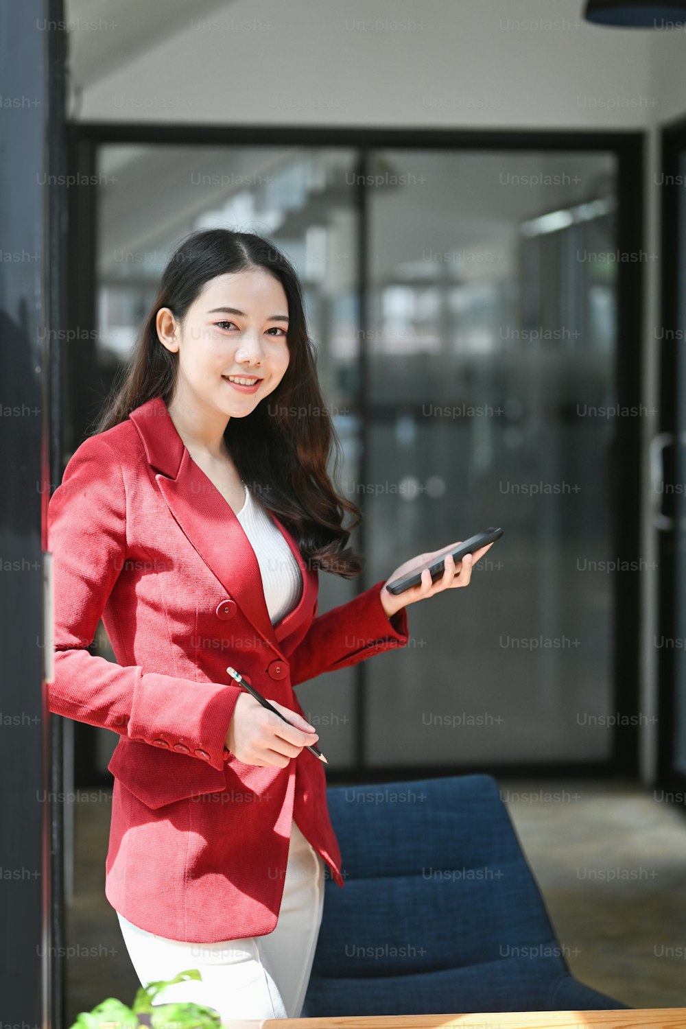 Portrait of confident businesswoman standing in office and smiling too camera.