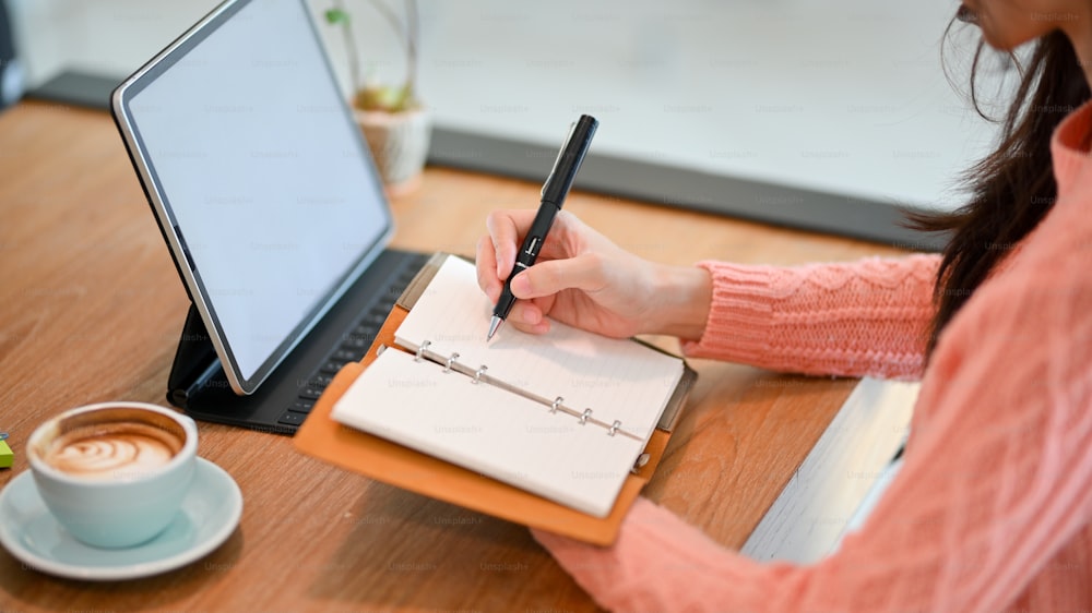 Jeune femme d’affaires asiatique gérant son emploi du temps pendant des semaines sur son agenda personnel tout en travaillant sur tablette. Maquette d’écran de tablette.