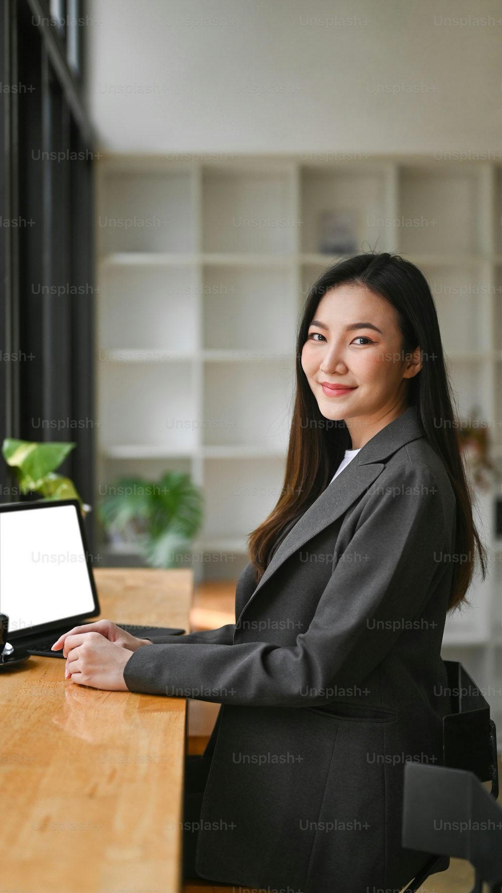 Attractive businesswoman using computer laptop and smiling to camera.