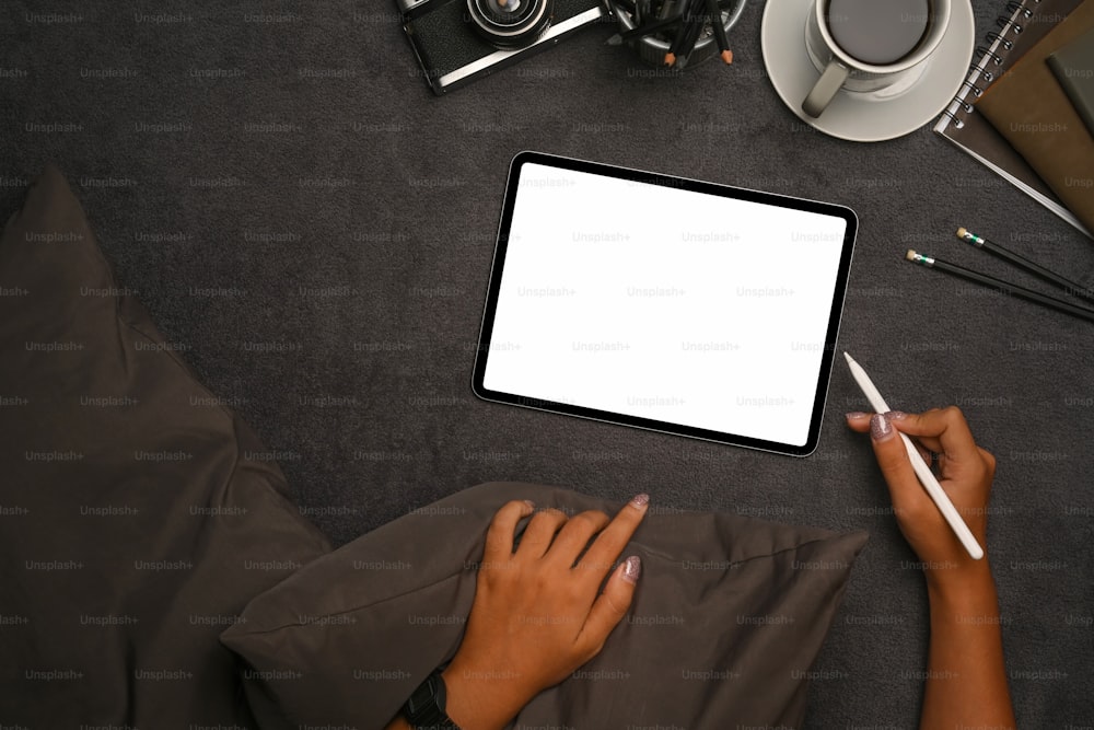 Frau mit digitalem Tablet auf grauem Teppich.