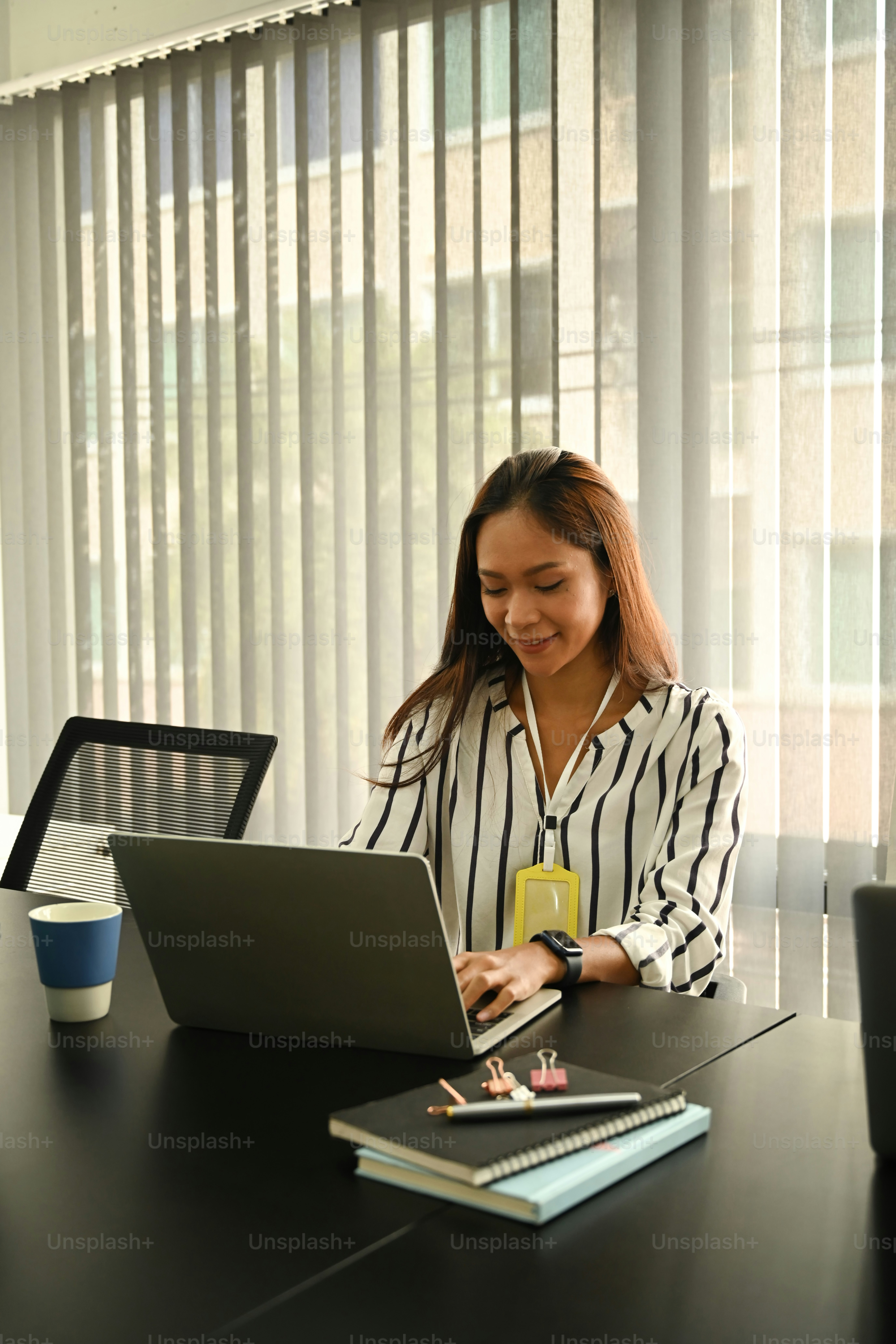 Empleada sonriente que trabaja con una computadora portátil en una oficina brillante.