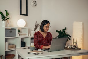Schöne Frau, die einen Laptop benutzt, während sie ihr Geschäft verwaltet und von zu Hause aus arbeitet