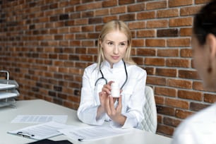 Female nurse explain daily dosage of painkiller medicine. Physician in white coat uniform prescribe drugs or pills to patient, talking with client in office at hospital. Healthcare concept
