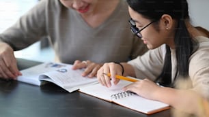 Private tutor helping young student doing homework and lesson practice preparing exam.