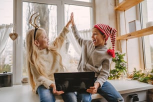 Boy and girl making video call using laptop at Christmas time. Selective focus.