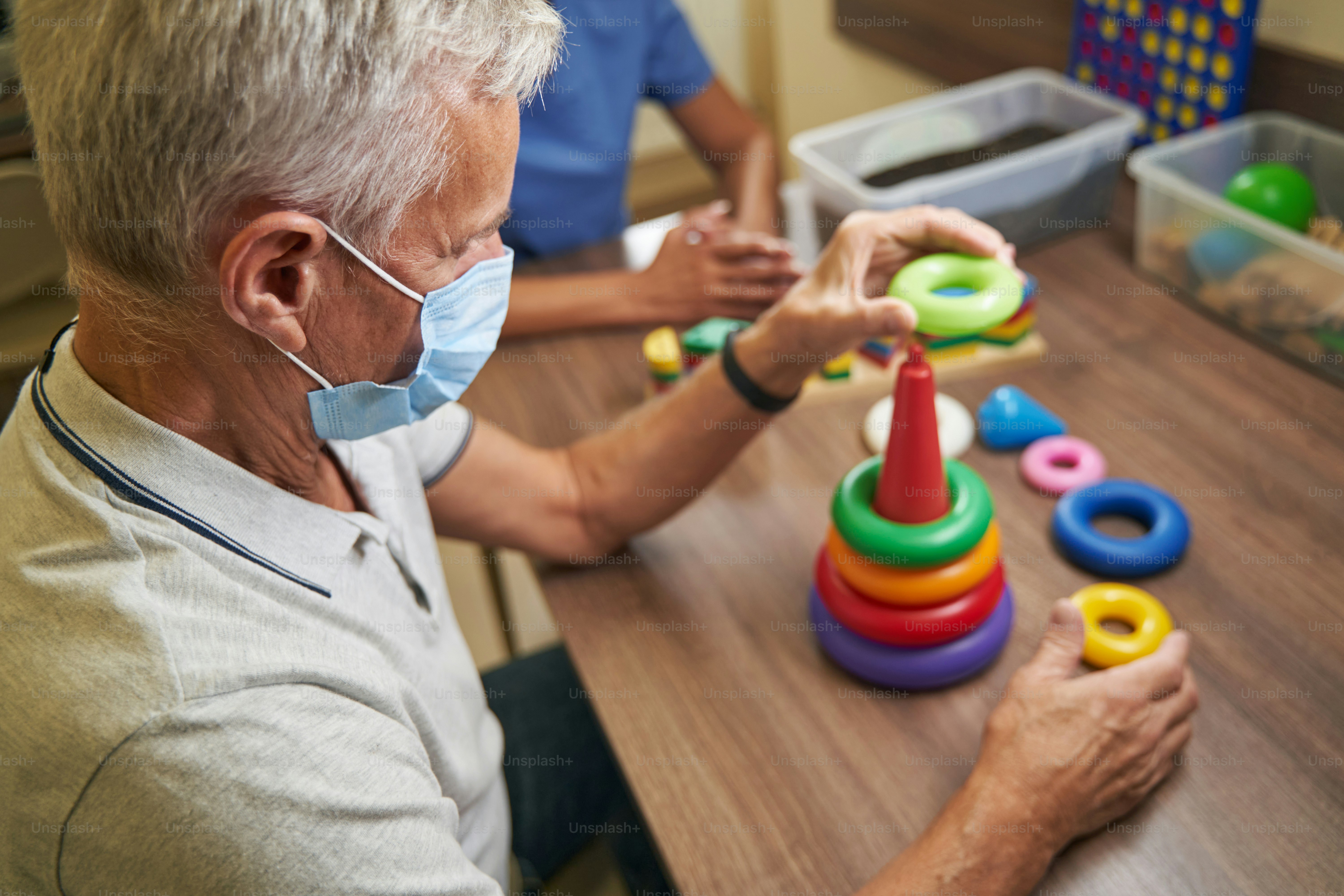 Stroke patient practicing activities for adaptive skills improving while using colorful physiotherapy equipment in medical center