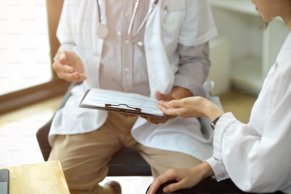 Imagen recortada de Un médico y un paciente discuten las opciones de tratamiento en un centro clínico médico.